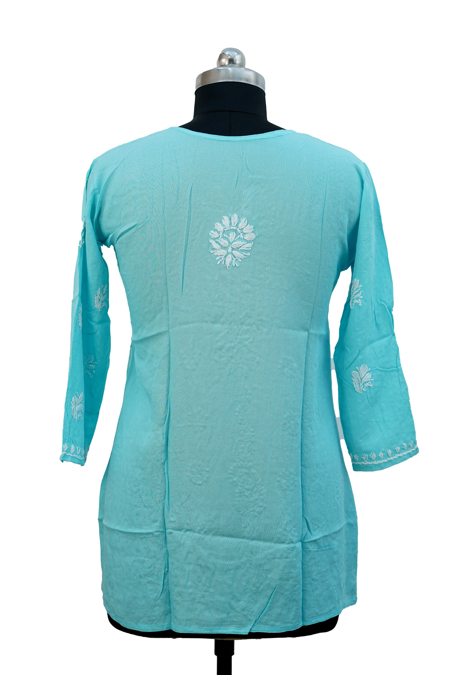 Turquoise dress with white floral embroidery on a mannequin against a white background
