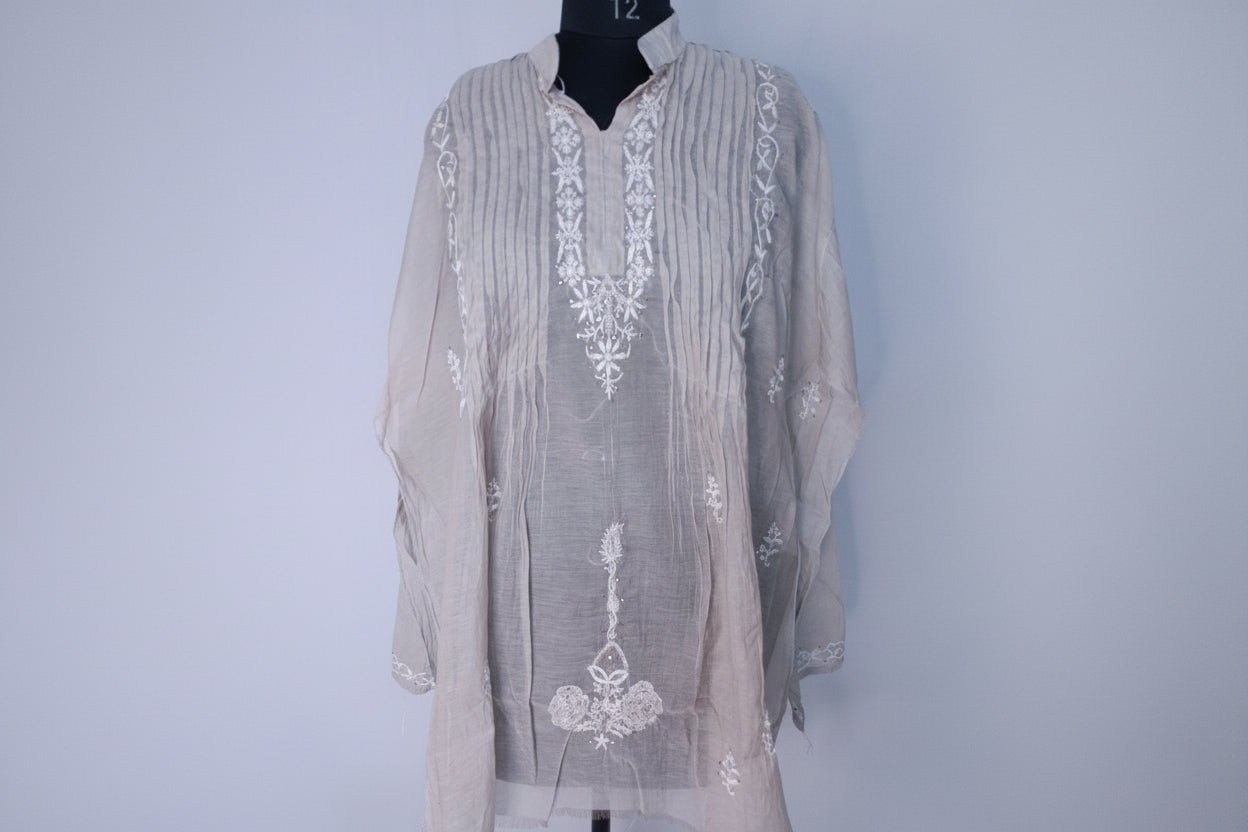 Light gray embroidered shirt on a mannequin against a light blue background