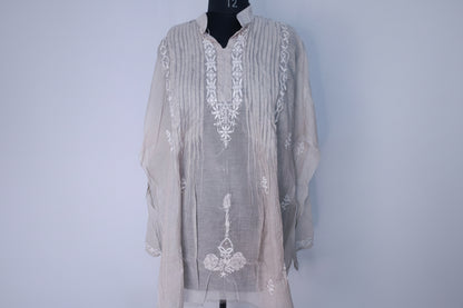 Light gray embroidered shirt on a mannequin against a light blue background